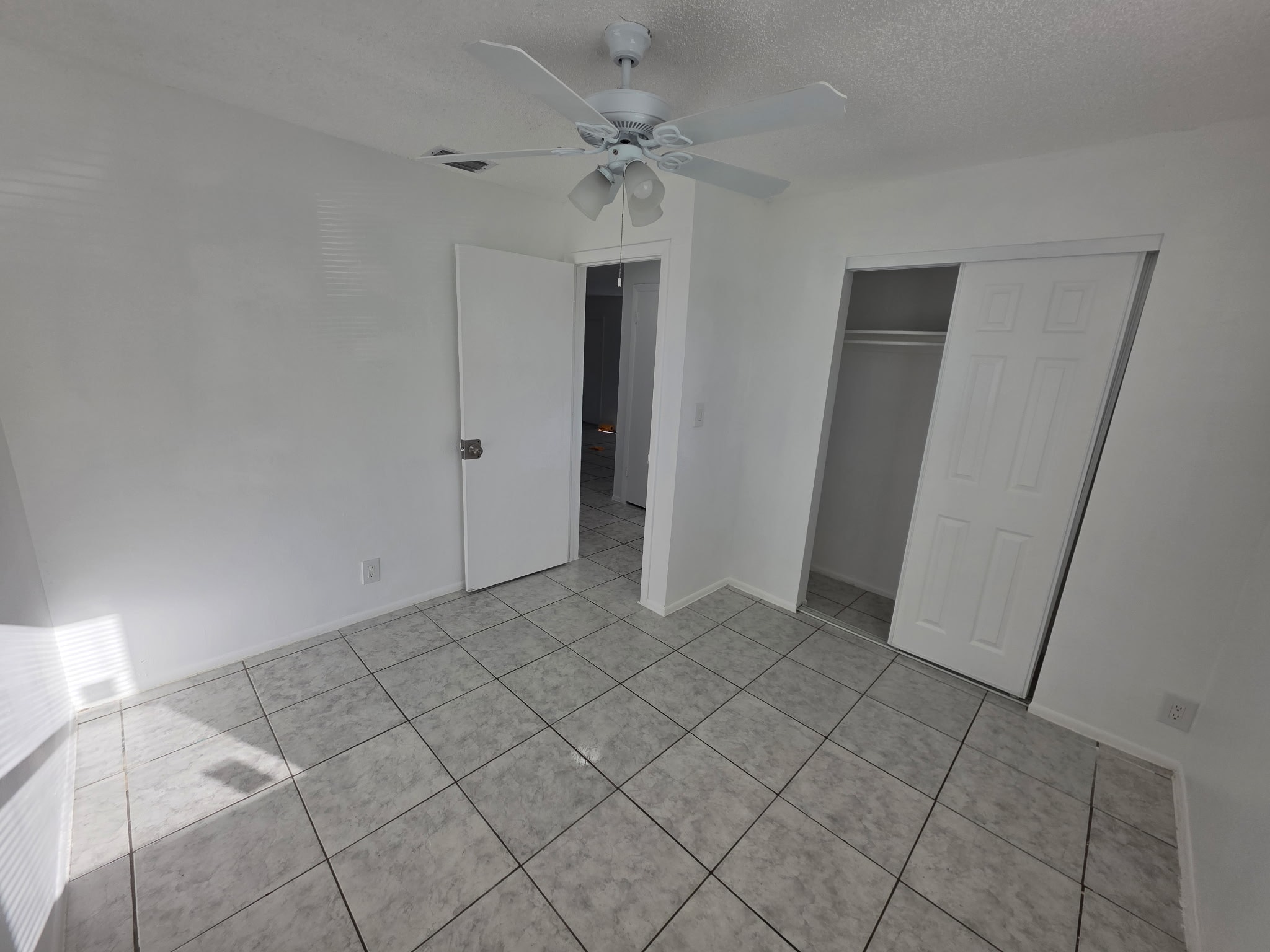 A room with a ceiling fan and tile flooring.