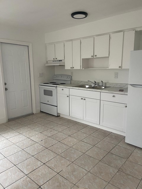 A kitchen with white cabinets and appliances.