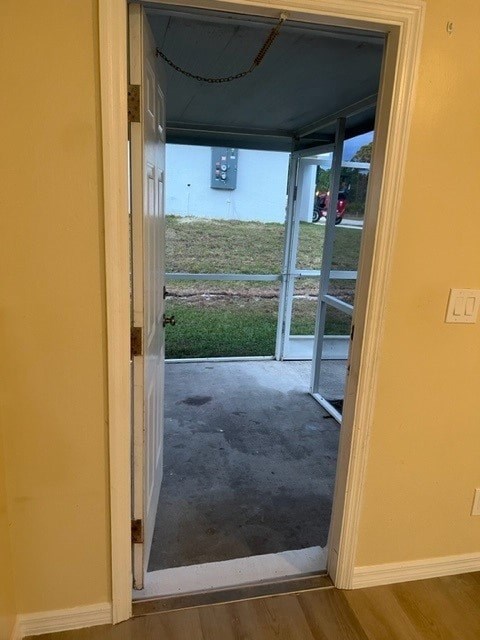A doorway opens to a patio with a view of a grassy area and a house.