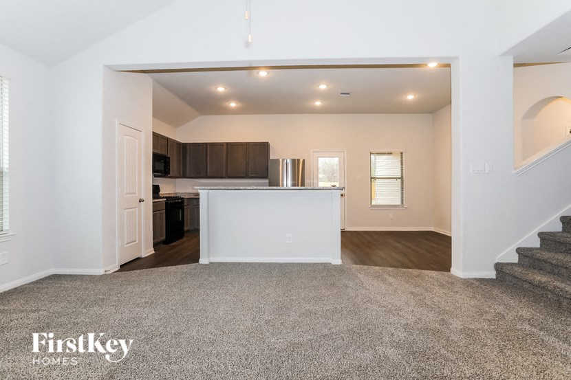 a renovated living room with a kitchen and stairs in a house