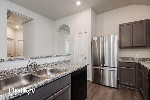 A kitchen with a stainless steel refrigerator and a granite countertop.