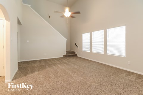 A spacious room with a staircase and a ceiling fan.