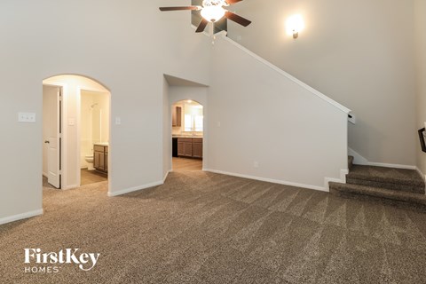 A spacious room with a carpeted floor and a staircase leading to another room.
