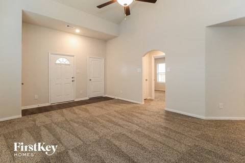 A spacious room with a carpeted floor and a ceiling fan.