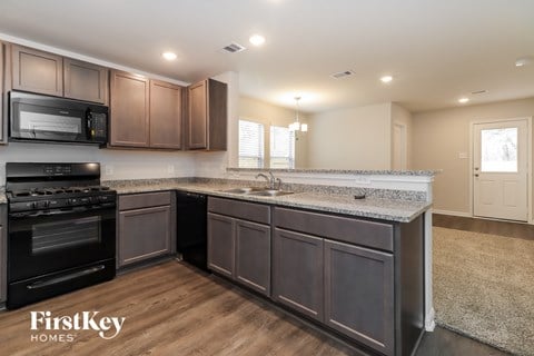 A kitchen with dark wood cabinets and a black stove top oven.