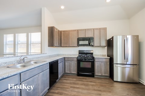 A kitchen with a stainless steel refrigerator and a black stove top oven.