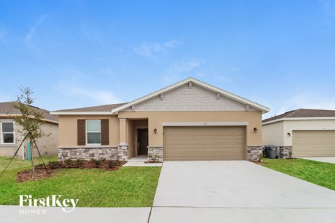 a beige house with a garage door and grass