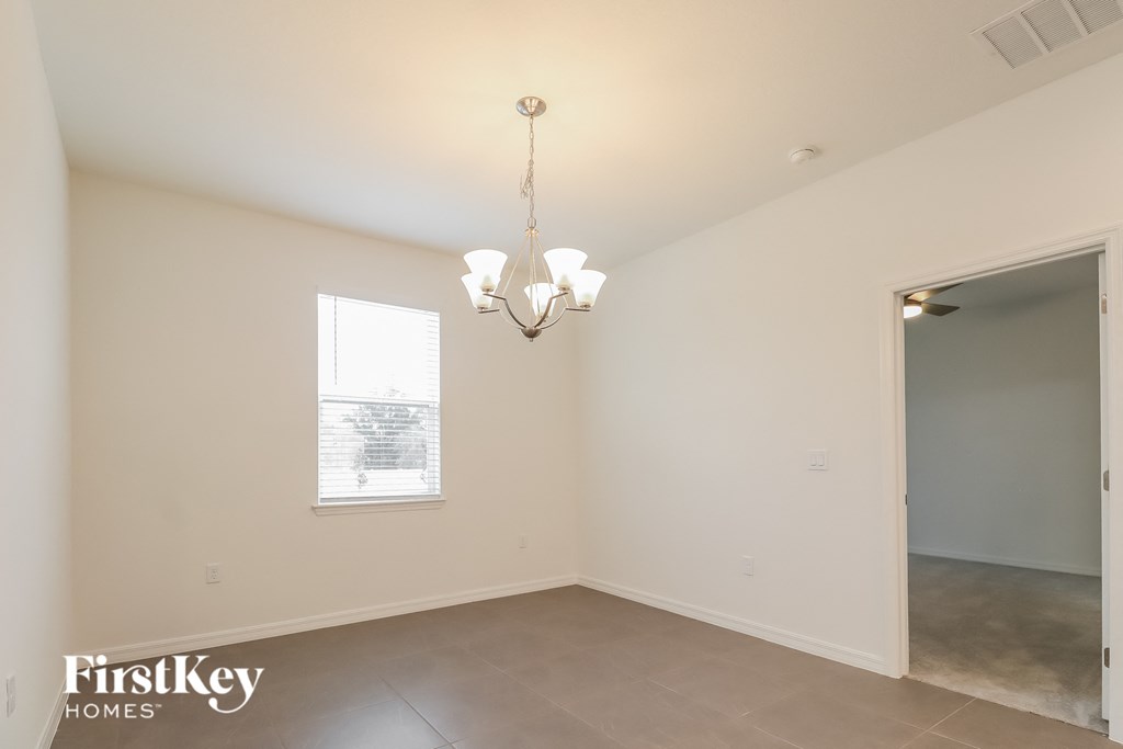 the living room and dining room of an empty house with a chandelier