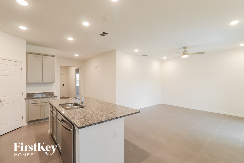 a kitchen and living room with white cabinets and a granite counter top