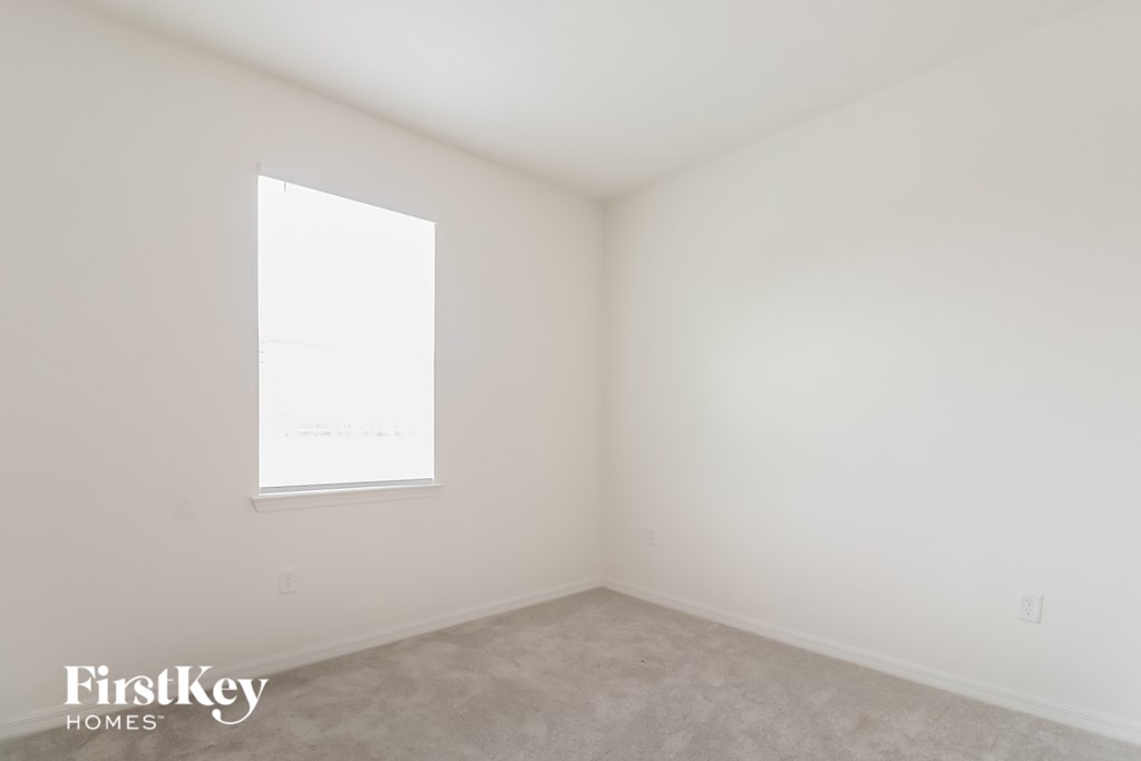 a bedroom with white walls and a window