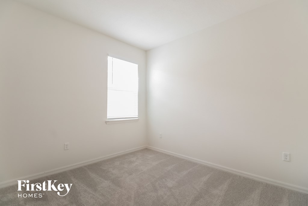 a bedroom with white walls and a window