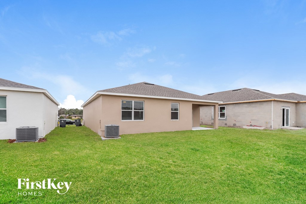 a beige house with a grassy yard and a blue sky