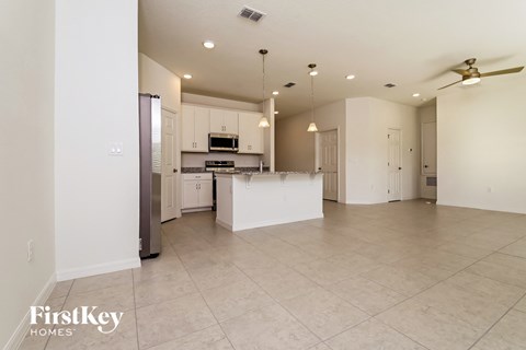 an open kitchen and living room with white cabinets and tile flooring