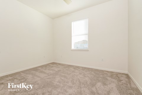 a bedroom with white walls and carpet and a window