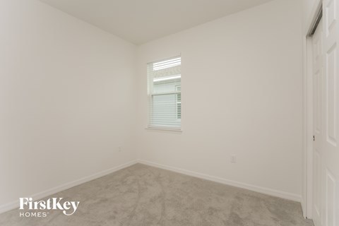 a bedroom with white walls and carpet and a window