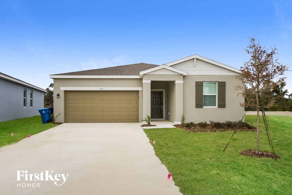 a beige house with a driveway and a garage door