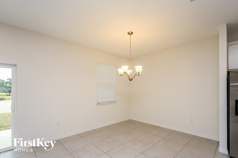 an empty dining room with white walls and tiled floor