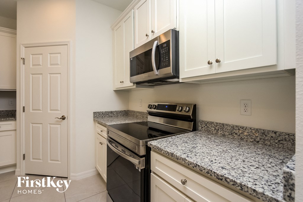 a kitchen with white cabinets and black appliances and granite counter tops
