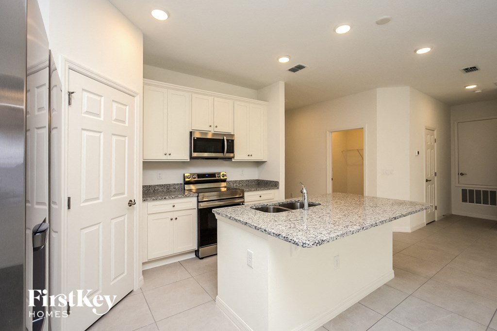 a large kitchen with white cabinets and granite counter tops