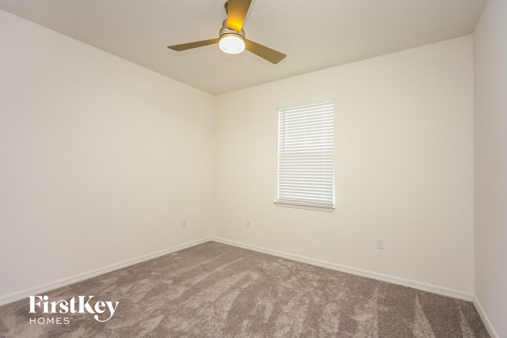 a bedroom with a ceiling fan and a carpeted floor