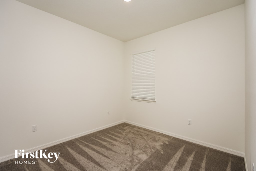 a bedroom with white walls and carpet and a window