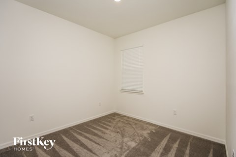 a bedroom with white walls and carpet and a window