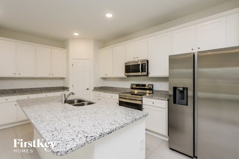 A kitchen with a granite countertop and stainless steel appliances.