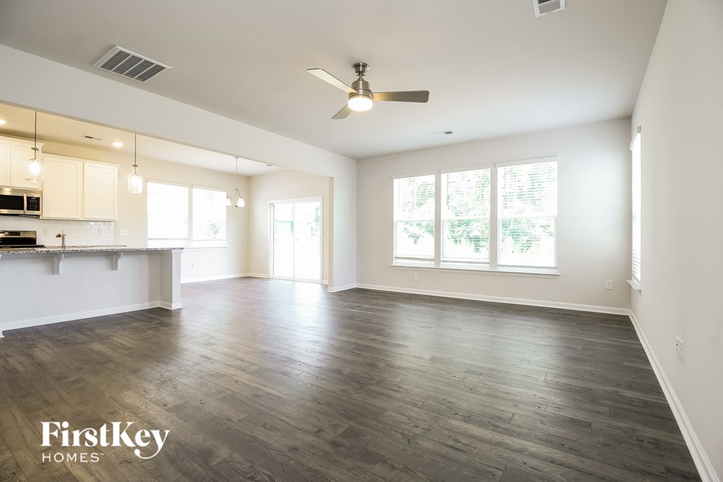 A spacious living room with wooden flooring and a ceiling fan.