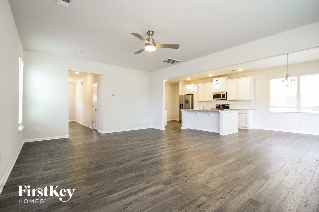 A spacious room with wooden flooring and a ceiling fan.