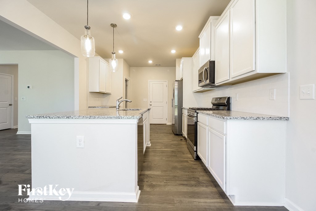 A kitchen with white cabinets and a marble countertop.