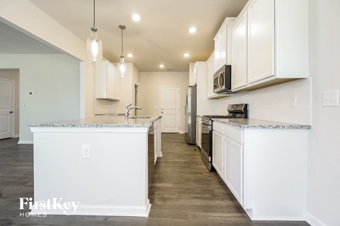 A kitchen with white cabinets and a marble countertop.