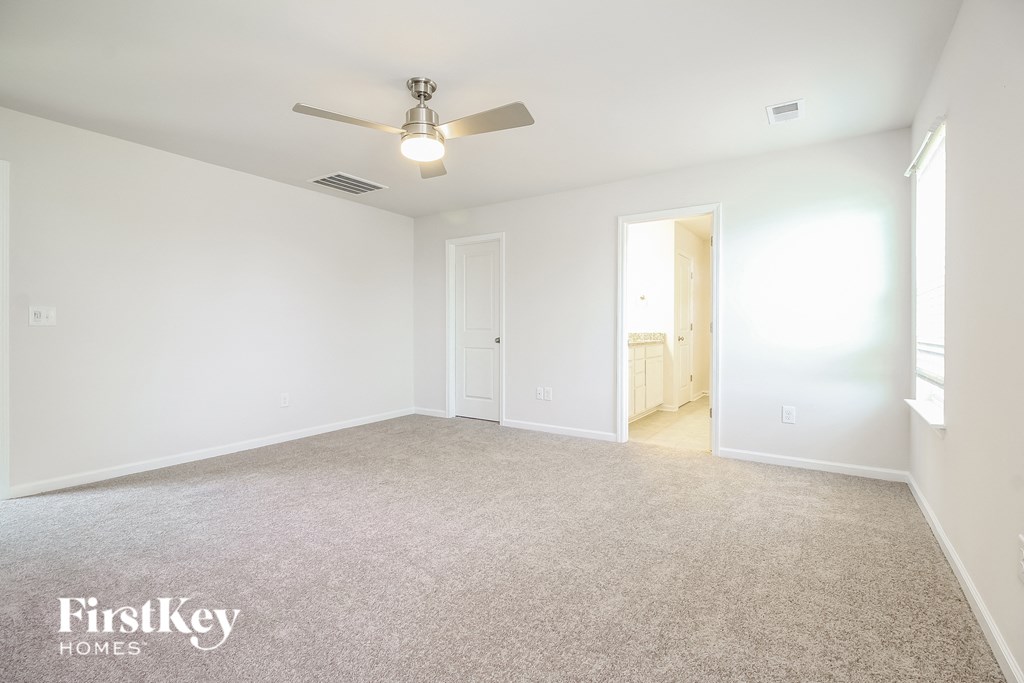 A spacious room with a ceiling fan and carpeted floor.