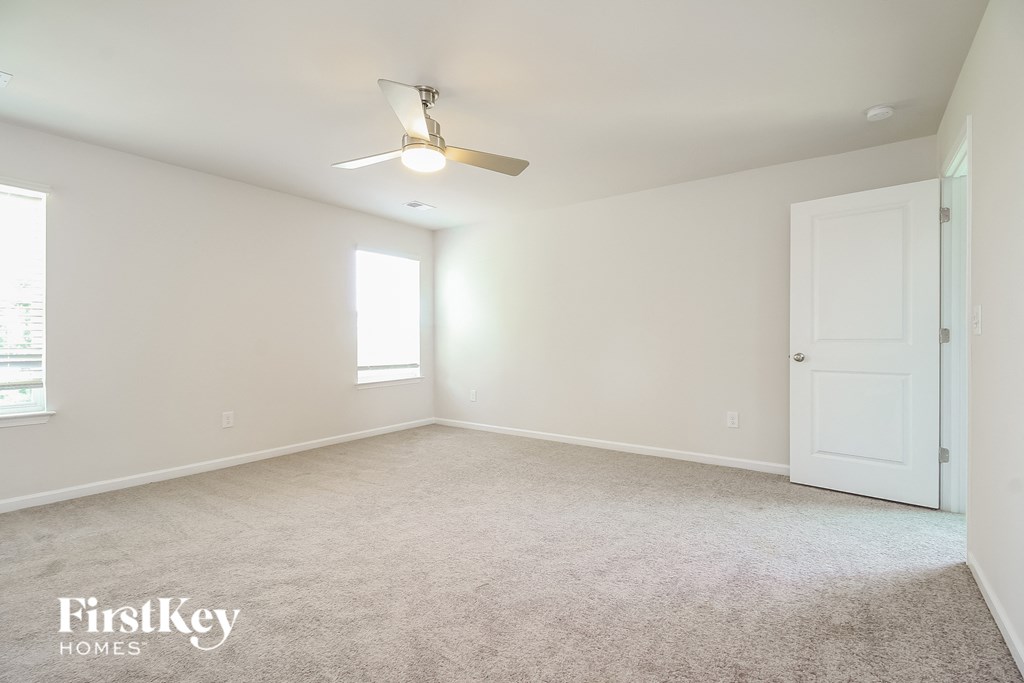 A spacious room with a ceiling fan and a door.