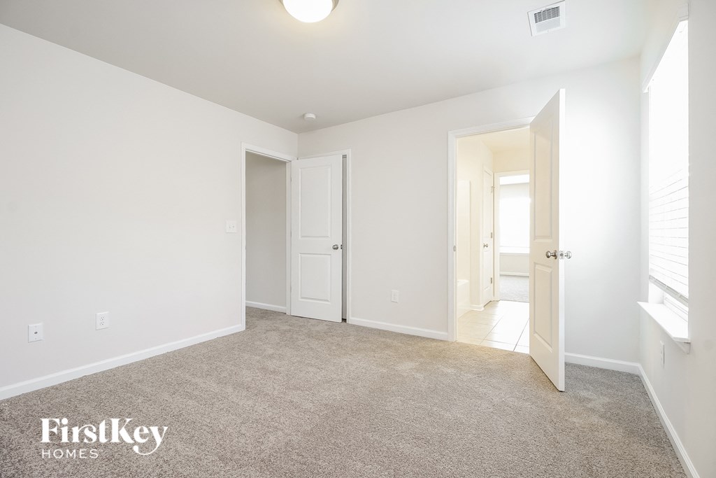 A carpeted room with a doorway leading to another room.