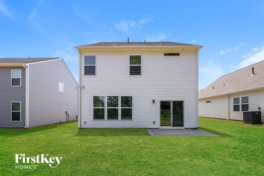 A white house with a grey roof and a green lawn in front.