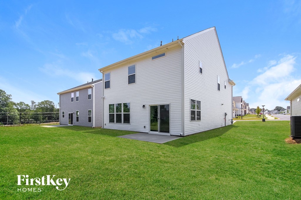 A white house with a yellow roof and a sign that says "FirstKey Homes" in front of it.