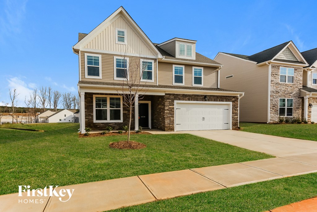 A house with a brown garage door and a tree in front of it.