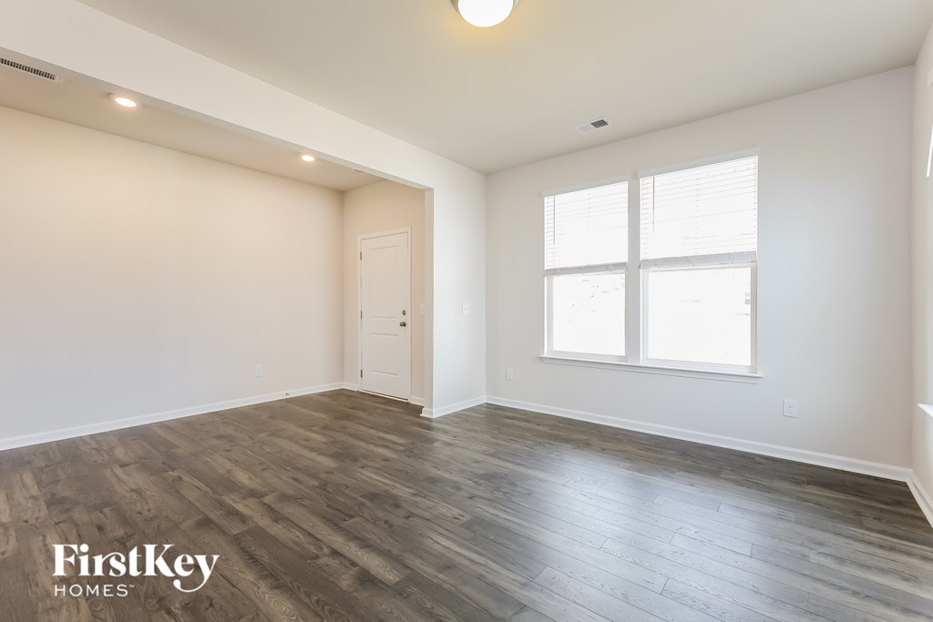 A spacious room with wooden flooring and a large window.