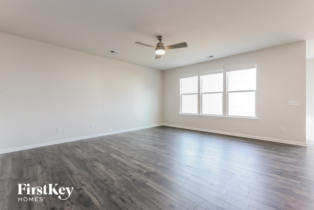 A spacious room with a ceiling fan and large windows.