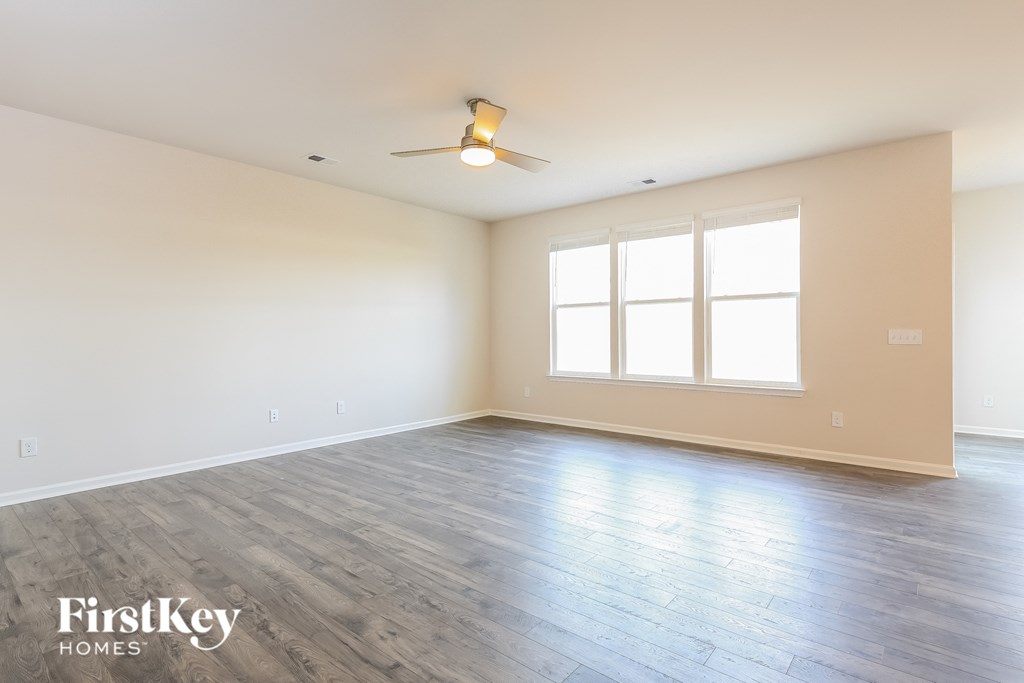 A spacious room with a ceiling fan and large windows.