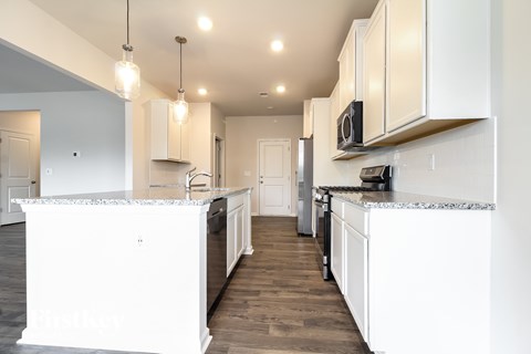 A kitchen with white cabinets and a black countertop.