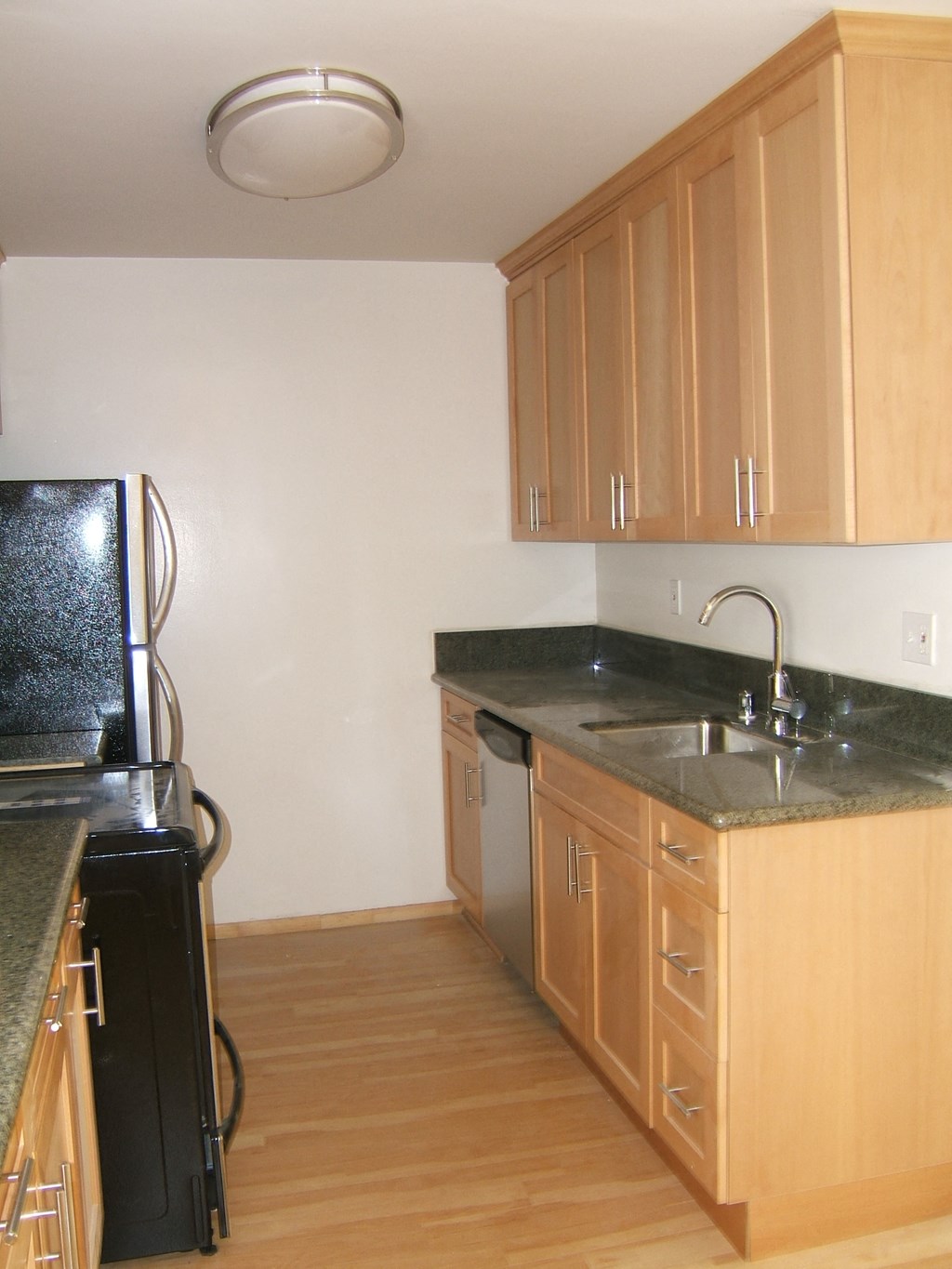 A kitchen with wooden cabinets and a black refrigerator.