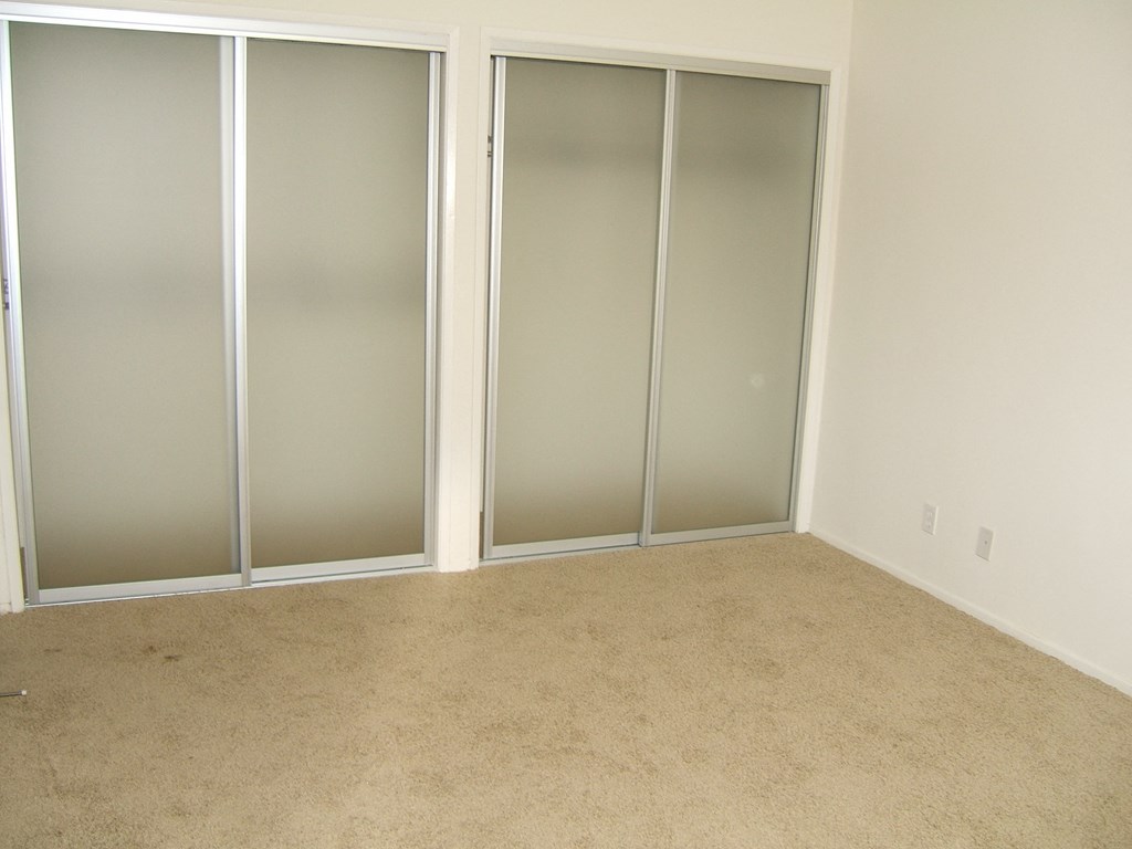 A room with a carpeted floor and three glass doors.