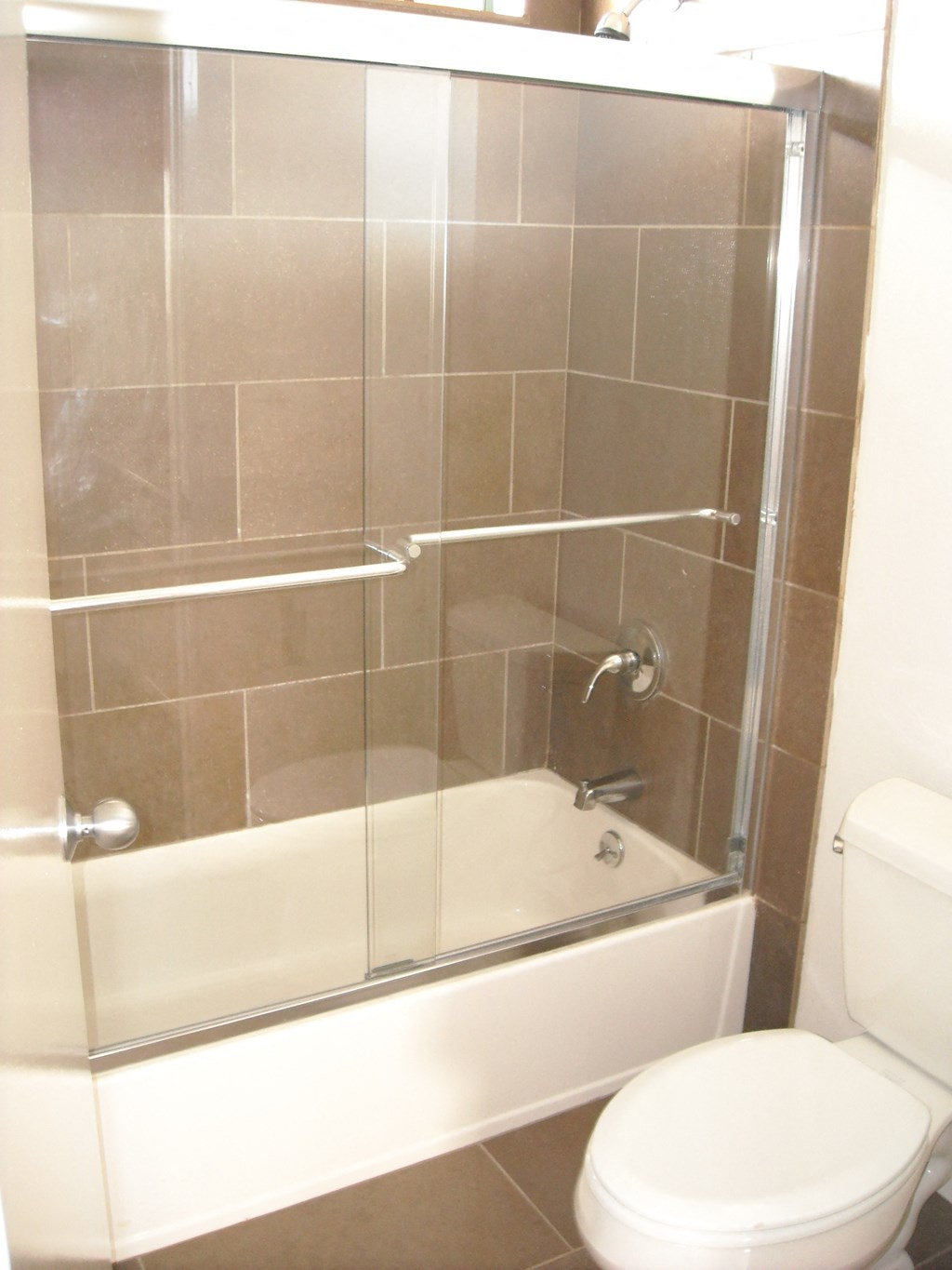 A white toilet sits next to a glass shower stall.