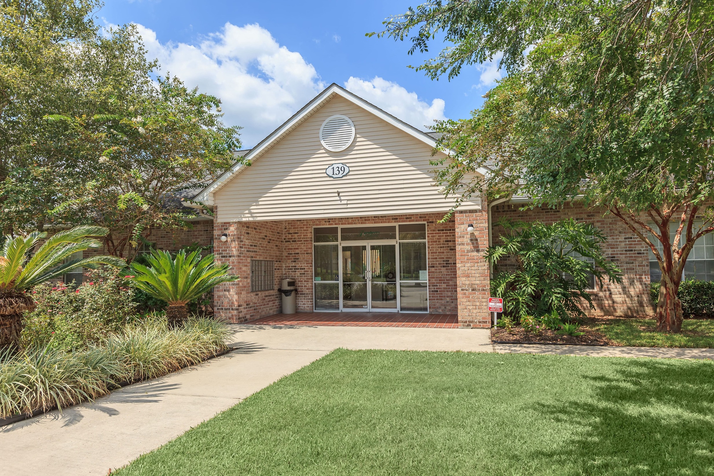 the front of a brick house with a lawn and trees