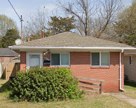 A small red brick house with a white door and windows.