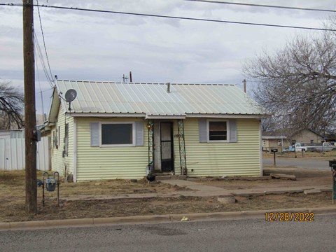 front view of a yellow house with a metal roof