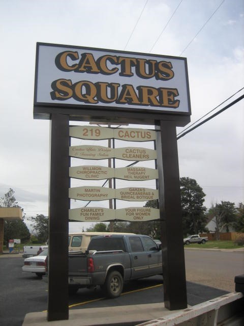 A sign for Cactus Square stands in front of a parking lot.