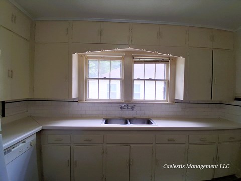 A kitchen with white cabinets and a window above the sink.