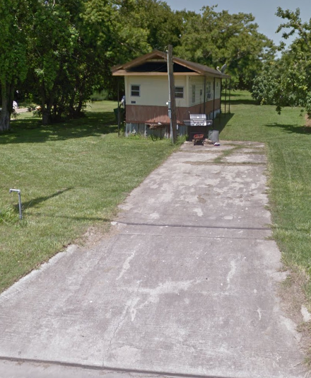 A concrete pathway leads to a small house.